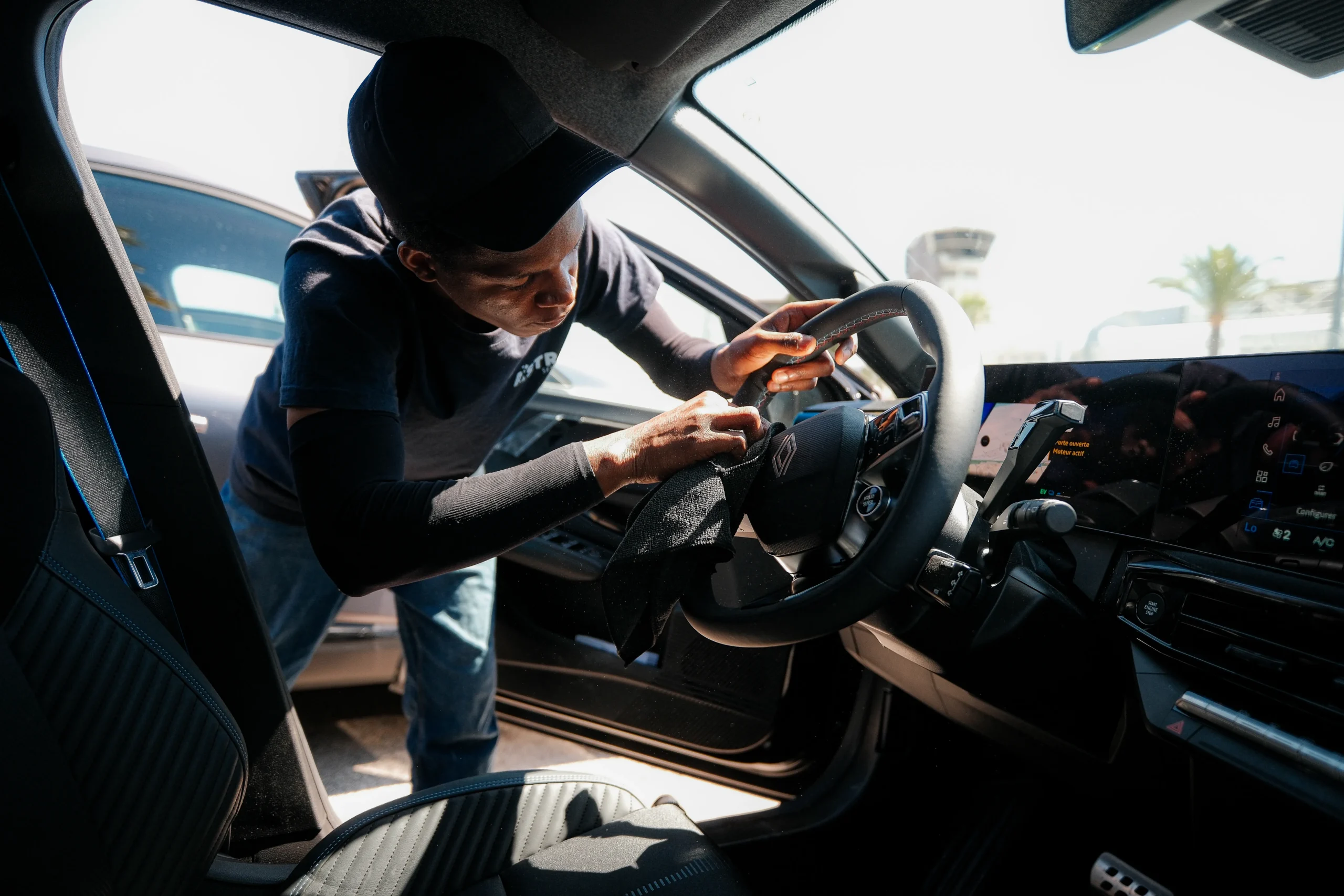 Agent de nettoyage frottant minutieusement le volant en cuir d'un véhicule