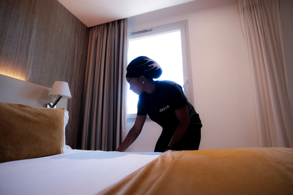 Femme de chambre bordant les draps blancs d'un lit d'hôtel